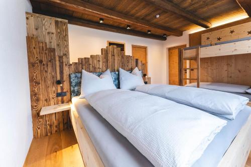 two beds in a bedroom with wooden walls at Egorta - Egarterhof Sexten in Sesto
