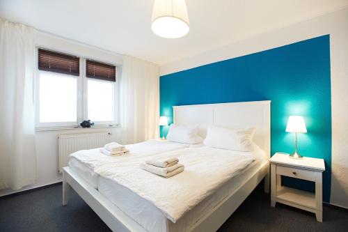 a bedroom with a large white bed with a blue wall at Haus Strandeck Nordstrand 18 in Göhren