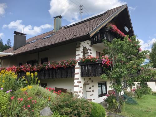 a white house with flowers on the balconies at Haus Hubertus in Enzklösterle