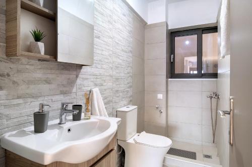 een witte badkamer met een wastafel en een toilet bij Oceanida Sofia Luxury Suite in Nikiana
