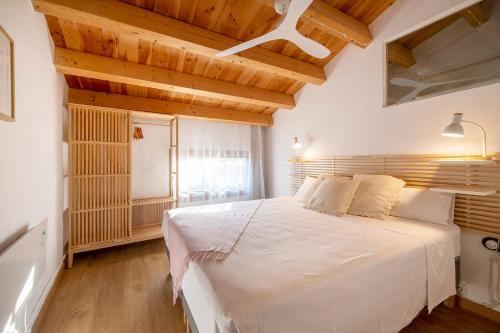 a bedroom with a large white bed with wooden ceilings at L'Altell in Montagut