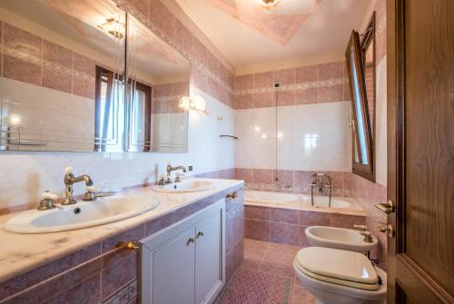 a bathroom with two sinks and a toilet and a mirror at Villa Vanna - Certaldo in Vico dʼElsa