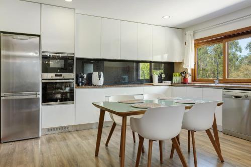 a kitchen with white cabinets and a table and chairs at Vermarl - Viana do Castelo in Linhares de Cima