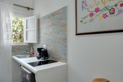 a white kitchen with a sink and a window at Politimis Studio N2 in Amorgos