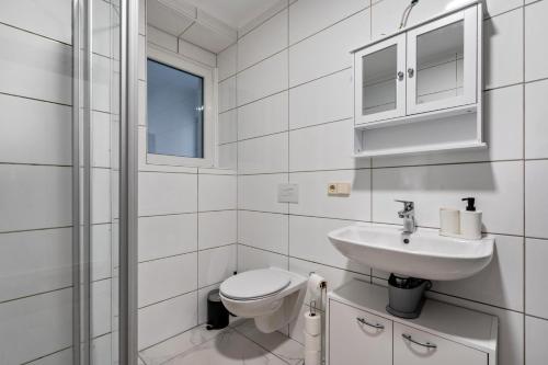a white bathroom with a toilet and a sink at Ferienwohnung Am Theaterplatz in Gera