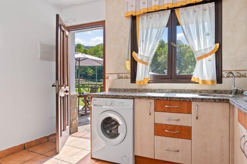 a kitchen with a washing machine and a window at Huerta El Pozu in Soto de las Dueñas