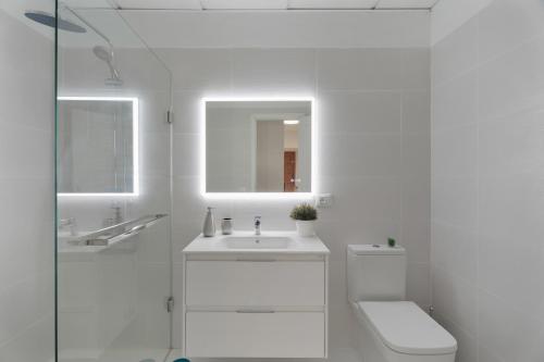 a white bathroom with a toilet and a sink at Apartamento Bonjour in Candelaria