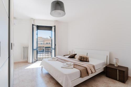 a white bedroom with a bed and a large window at Casa Idrusa a Otranto in Otranto