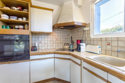 a kitchen with white cabinets and a sink and a window at Grande maison familiale in Douarnenez