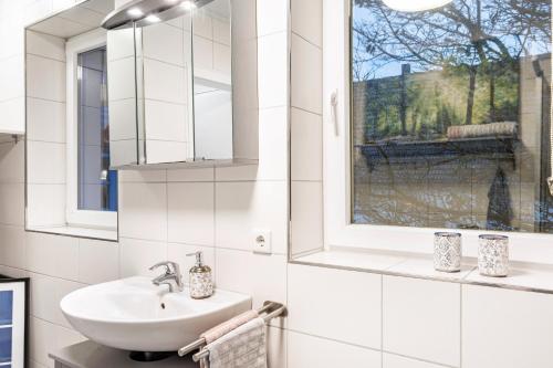 a white bathroom with a sink and a window at Ferienwohnung im Torwärterhäuschen in Rüthen