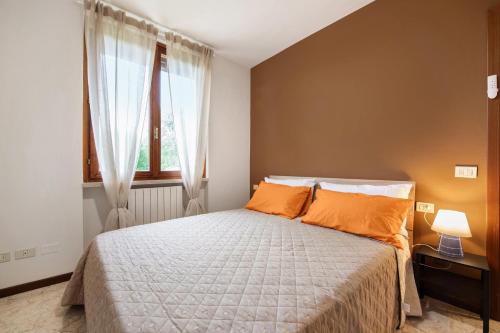 a bedroom with a bed with orange pillows and a window at vista lago apartment 1 in Soiano del Lago