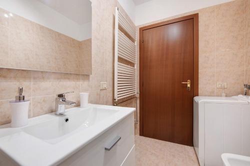 a bathroom with a white sink and a wooden door at vista lago apartment 1 in Soiano del Lago