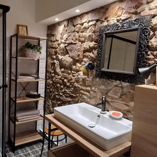 a bathroom with a sink and a stone wall at Auszeit Rheingauer Rosengarten in Geisenheim