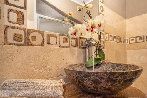 a bathroom with a sink with a vase with flowers in it at Casa a schiera Budoni in Budoni