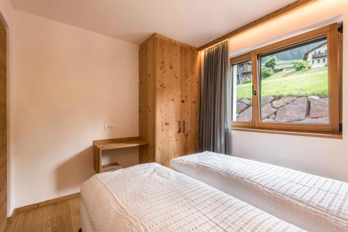 two beds in a bedroom with a window at Apt Lara Siela in Ortisei