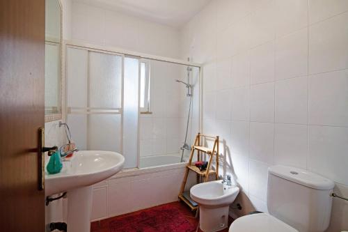 a white bathroom with a toilet and a sink at Villa Isabel in Loulé