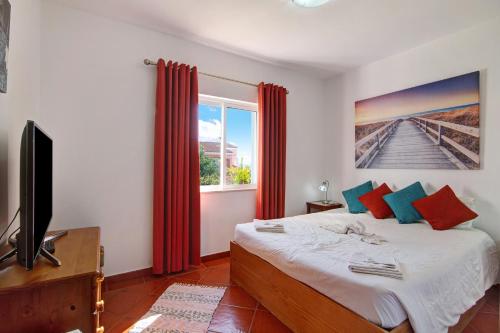 a bedroom with a bed with red curtains and a tv at Villa Isabel in Loulé