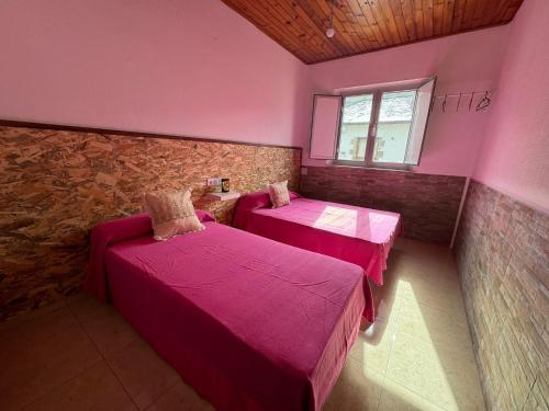 two beds in a room with pink walls and a window at O Lar Tuna in Pereiro