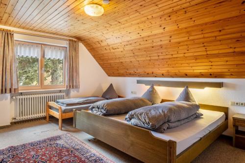 two beds in a room with a wooden ceiling at Haus Irmgard in Lenzkirch