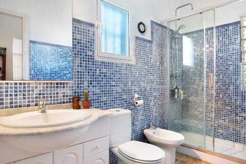 a blue tiled bathroom with a toilet and a sink at Casa Luna in Los Caños de Meca