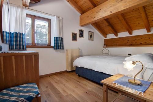 a bedroom with a bed and a table with a lamp at Ginepro Casa Vacanze in Madesimo