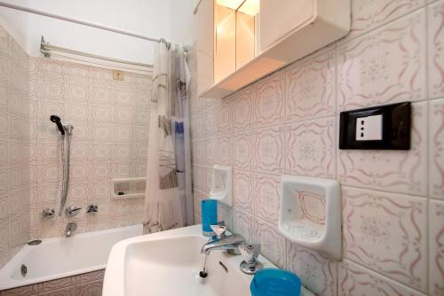 a bathroom with pink wallpaper and a sink and a tub at Casa Lulu' in Lavagna
