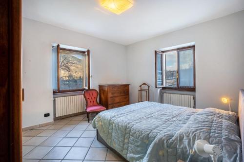 a bedroom with a bed and a chair and windows at Casa Daniela in Druogno