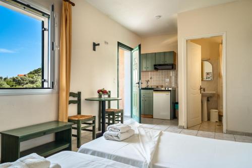 a room with a bed and a kitchen with a window at Anemona studio E in Kefallonia