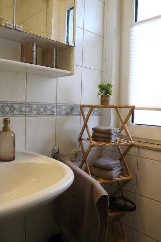 a bathroom with a sink and a shelf with towels at Apartment Gartenblick in Korbach