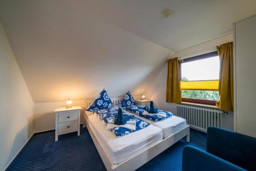 a bedroom with a bed with blue pillows and a window at Olde Toornblick in Borkum