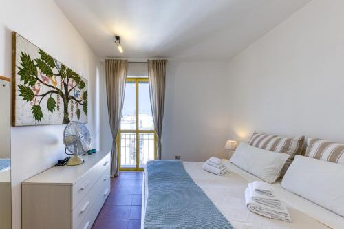 a white bedroom with a bed and a window at Bouganville in Leuca