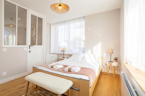 a white bedroom with a bed and a chair at Le Pied-à-terre in Bénodet
