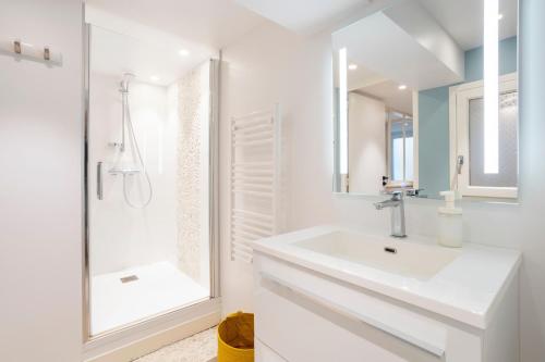 a white bathroom with a sink and a shower at Le Pied-à-terre in Bénodet