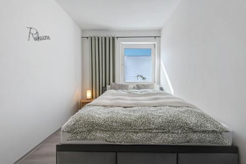 a white bedroom with a bed and a window at Ferienwohnung aufm Weinberg in Schwandorf in Bayern