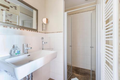 a white bathroom with a sink and a shower at Haevn-Erholung, Fewo Sodalith in Reußenköge