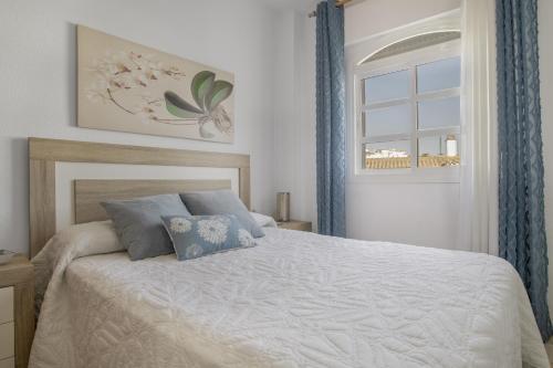 a bedroom with a bed with blue curtains and a window at Apartamento en Vejer in Vejer de la Frontera