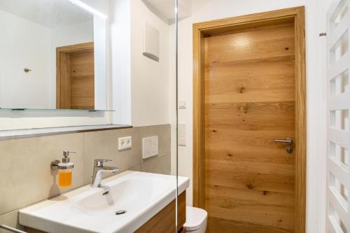 a bathroom with a sink and a wooden door at Beim Schweizer in Garmisch-Partenkirchen