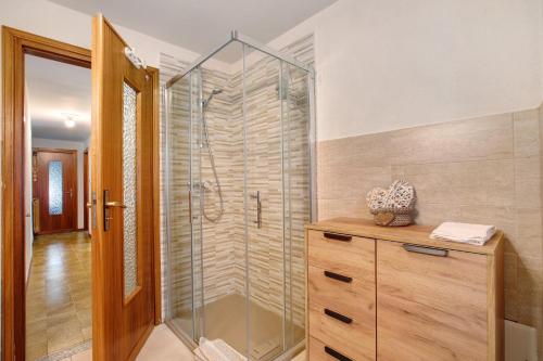 a bathroom with a glass shower and a wooden cabinet at Appartamento Delfine in La Salle