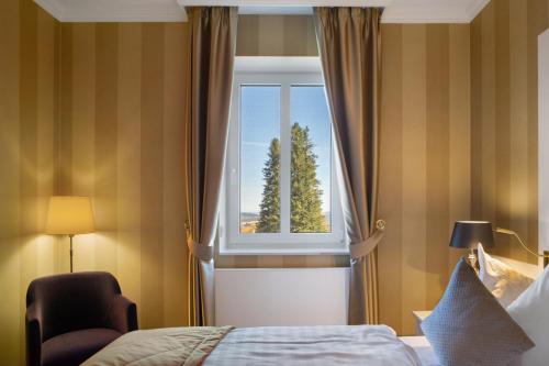 a bedroom with a bed and a window with a tree at Kurhaus Masserberg in Masserberg
