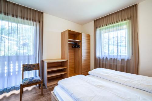 a bedroom with a bed and a chair and a window at Gartenheim App Martin in Schenna