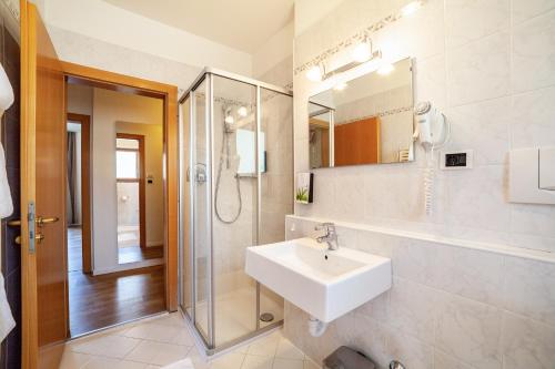 a white bathroom with a sink and a shower at Gartenheim App Martin in Schenna