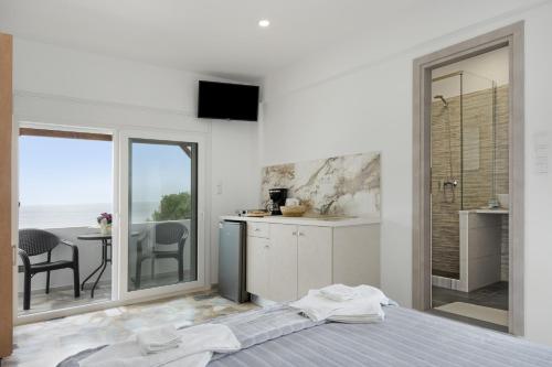 a bedroom with a bed and a kitchen with a balcony at Niki's Studios Kalymnos in Kalymnos