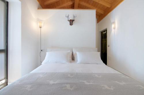 a bedroom with a large white bed with white pillows at Borgo Vico in Verceia