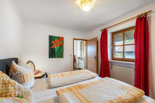 a bedroom with two beds and a window with red curtains at Landhaus Kauderer - Wohnung 2 in Waging am See