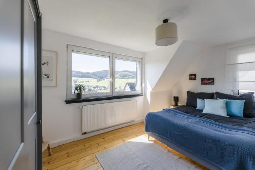 a bedroom with a blue bed and a window at Dorfhaus1953 in Eslohe