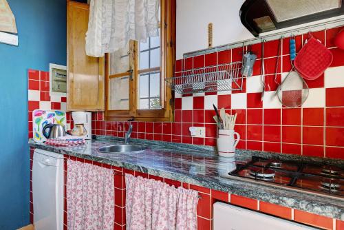 a kitchen with red and white tiles on the wall at La Ripa - Appartamento I Nidi in San Gimignano