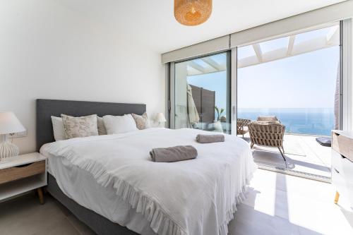 a white bedroom with a large bed and a balcony at Luxury Penthouse with Rooftop in Fuengirola