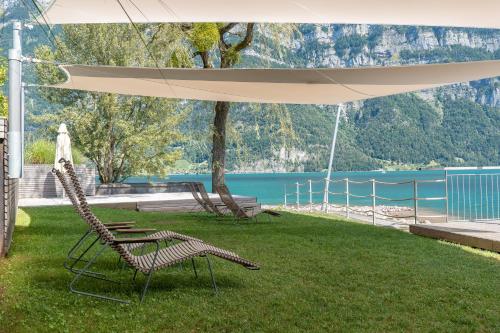 zwei Stühle stehen unter einem Sonnenschirm im Gras in der Unterkunft lofthotel Walensee in Murg