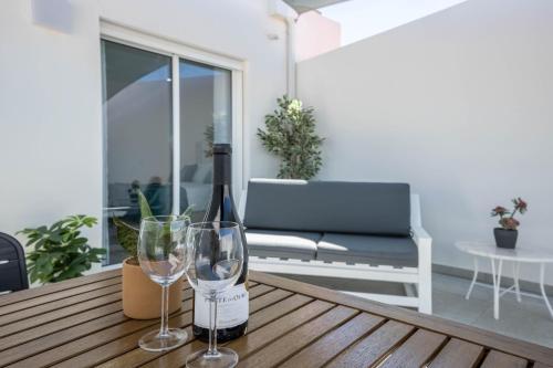 a bottle of wine and two wine glasses on a wooden table at Sunset Apartment in Sagres