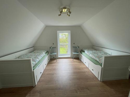a attic room with two beds and a window at Kleines Haus am Feld in Rehna